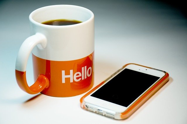 Coffee mug with an iPhone while working